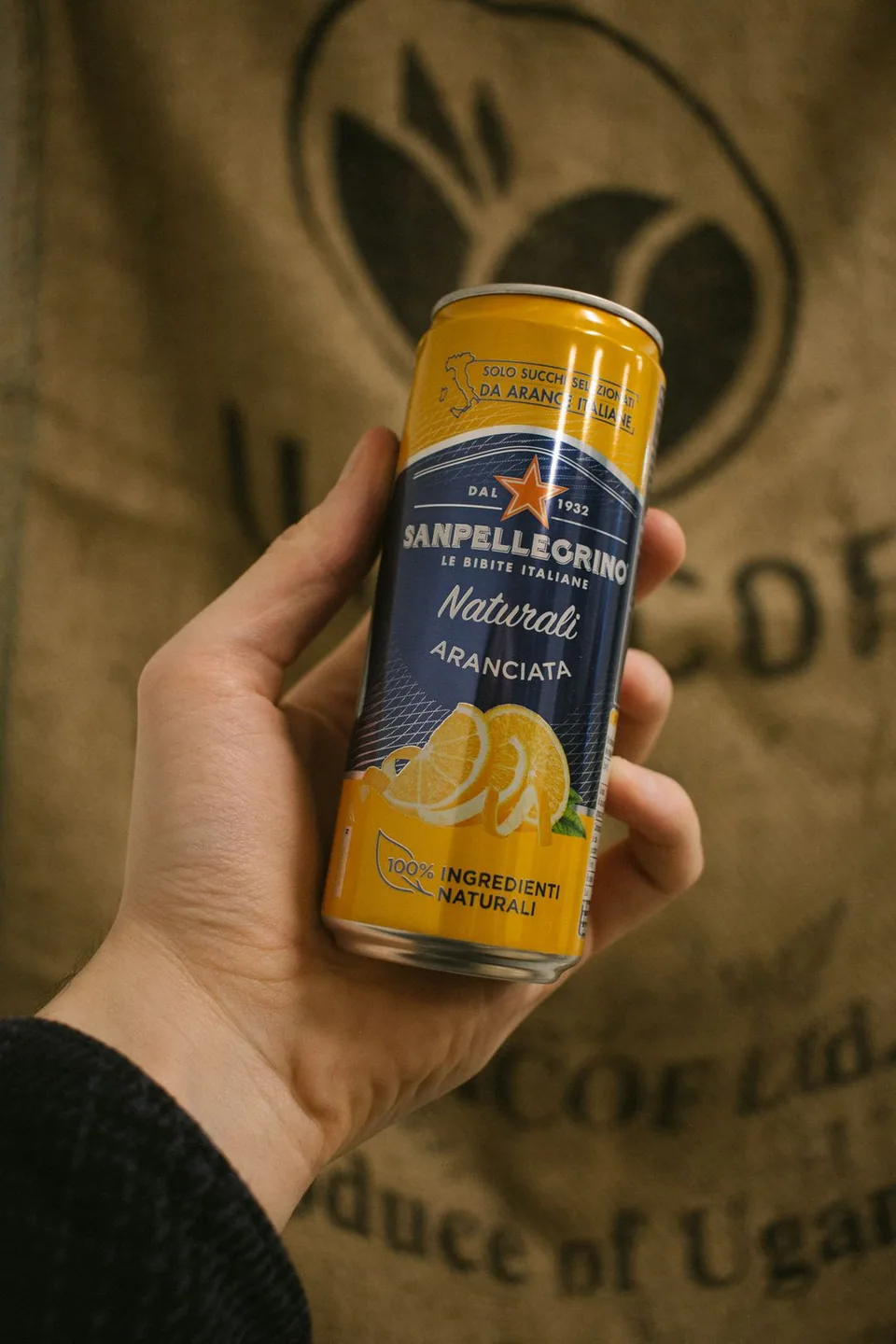 Sanpellegrino-appelsiinijuomatölkki kädessä